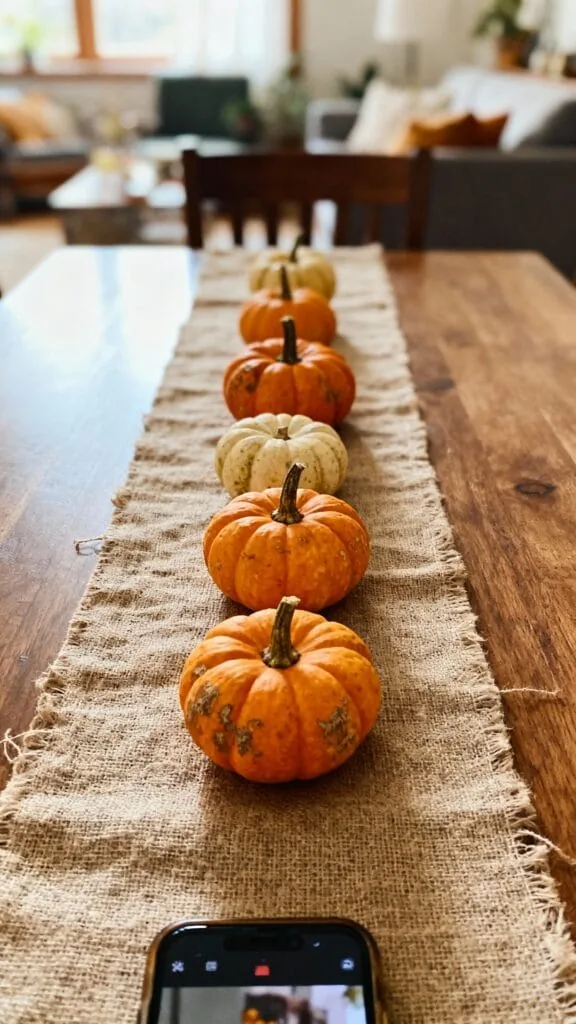 Mini pumpkin runner fall centerpiece on a linen table runner