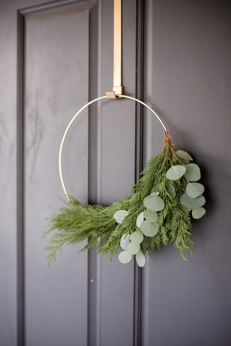 Minimalist gold hoop wreath with asymmetrical cedar and eucalyptus greenery on a charcoal door