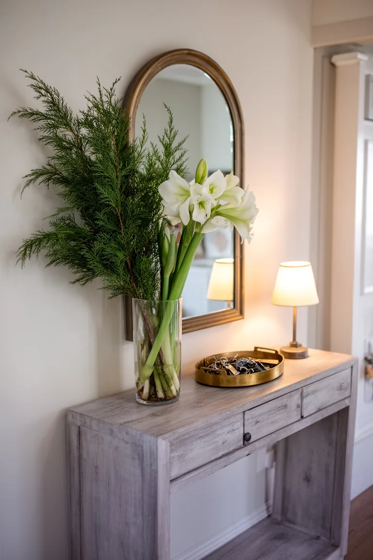 Console table with a centered mirror, evergreens and amaryllis, a lamp and a brass key tray
