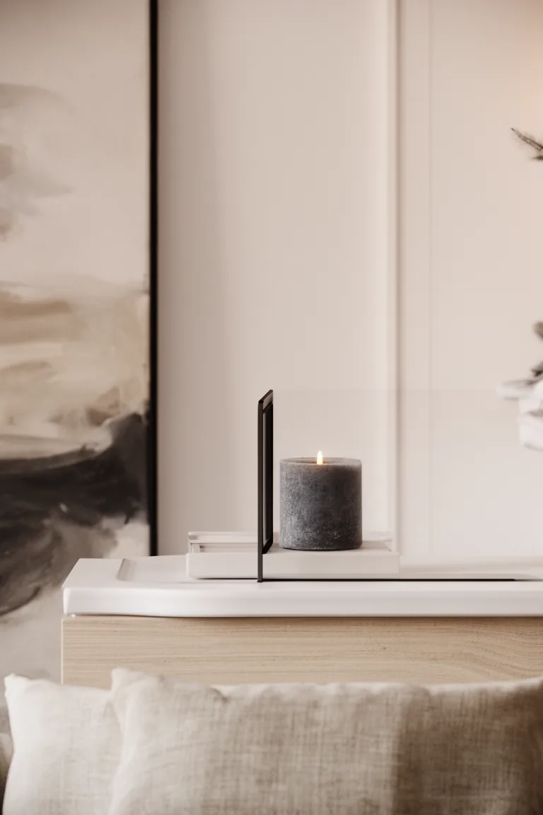 White-on-white vignette with charcoal candle and slim black frame