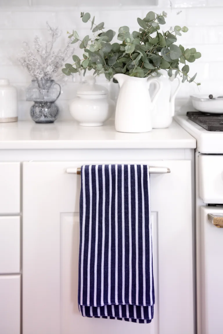White pitcher with eucalyptus and navy striped tea towel