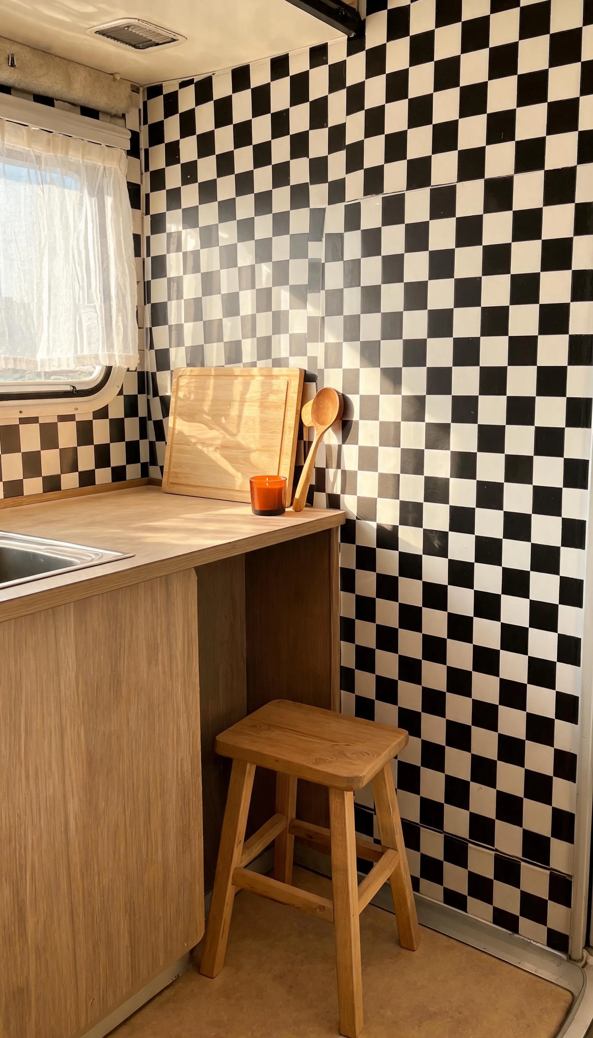 Camper kitchenette floor-to-wall black and white checkerboard peel-and-stick wallpaper with a small stool