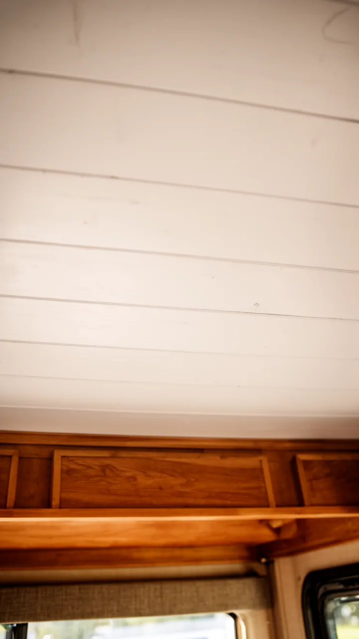 Horizontal white shiplap boards across a bright farmhouse-style camper ceiling