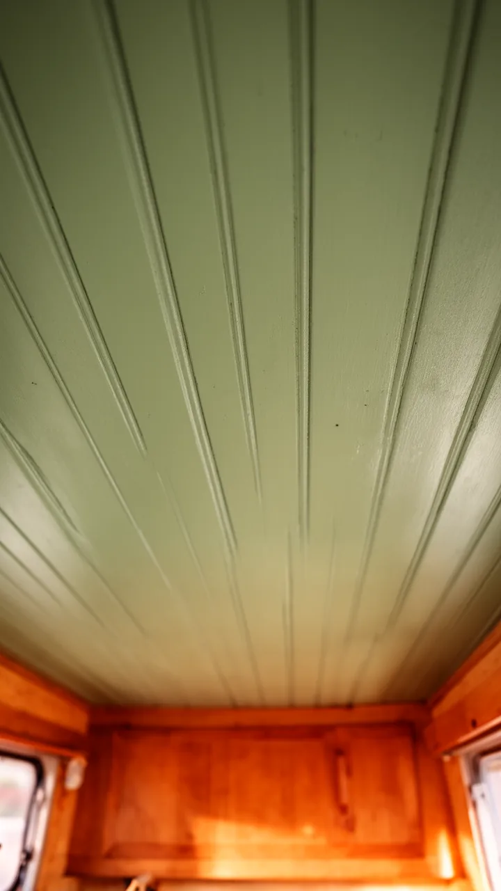 Evenly spaced soft sage painted wood slats adding gentle texture to a camper ceiling