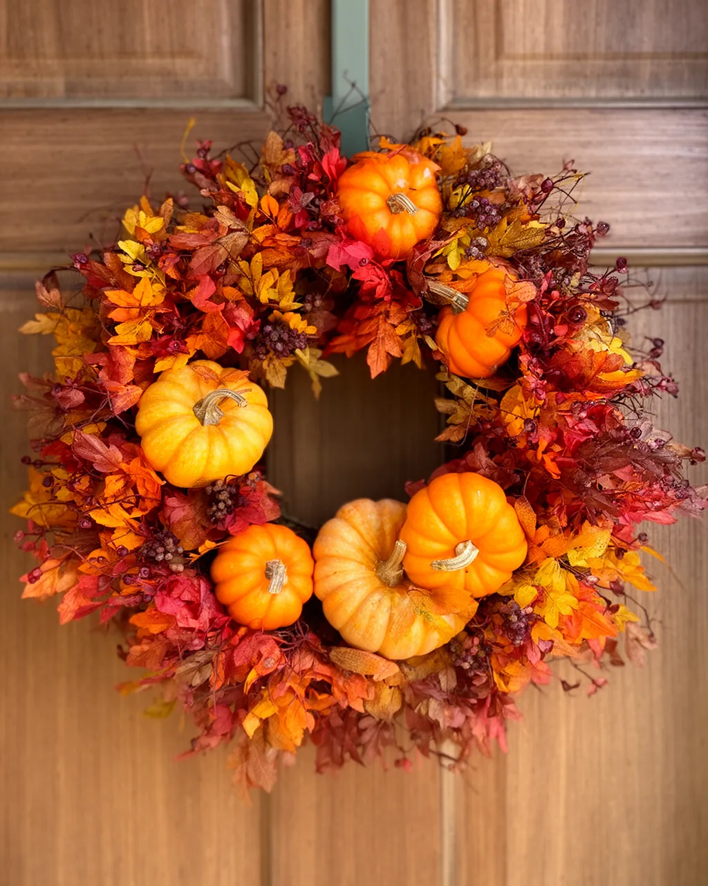 Fall wreath with mini pumpkins on a wood door