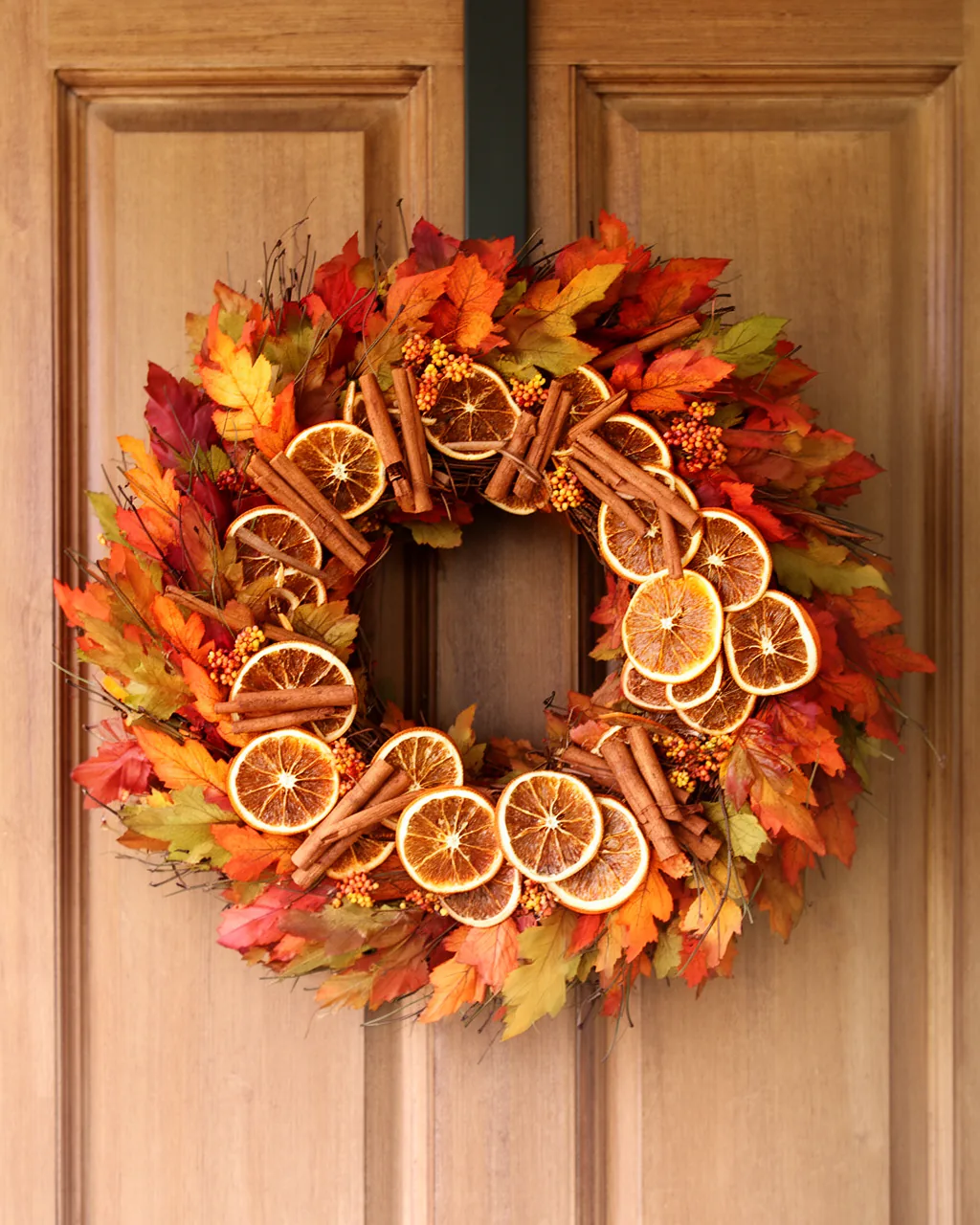Dried orange and cinnamon fall wreath on a wood door