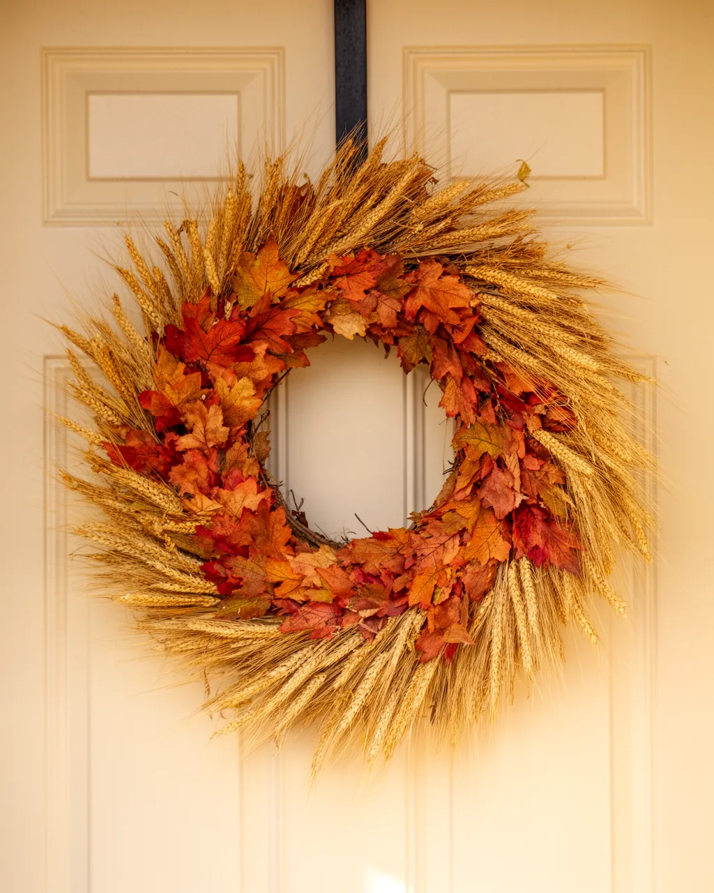 Golden wheat farmhouse fall wreath on a cream door