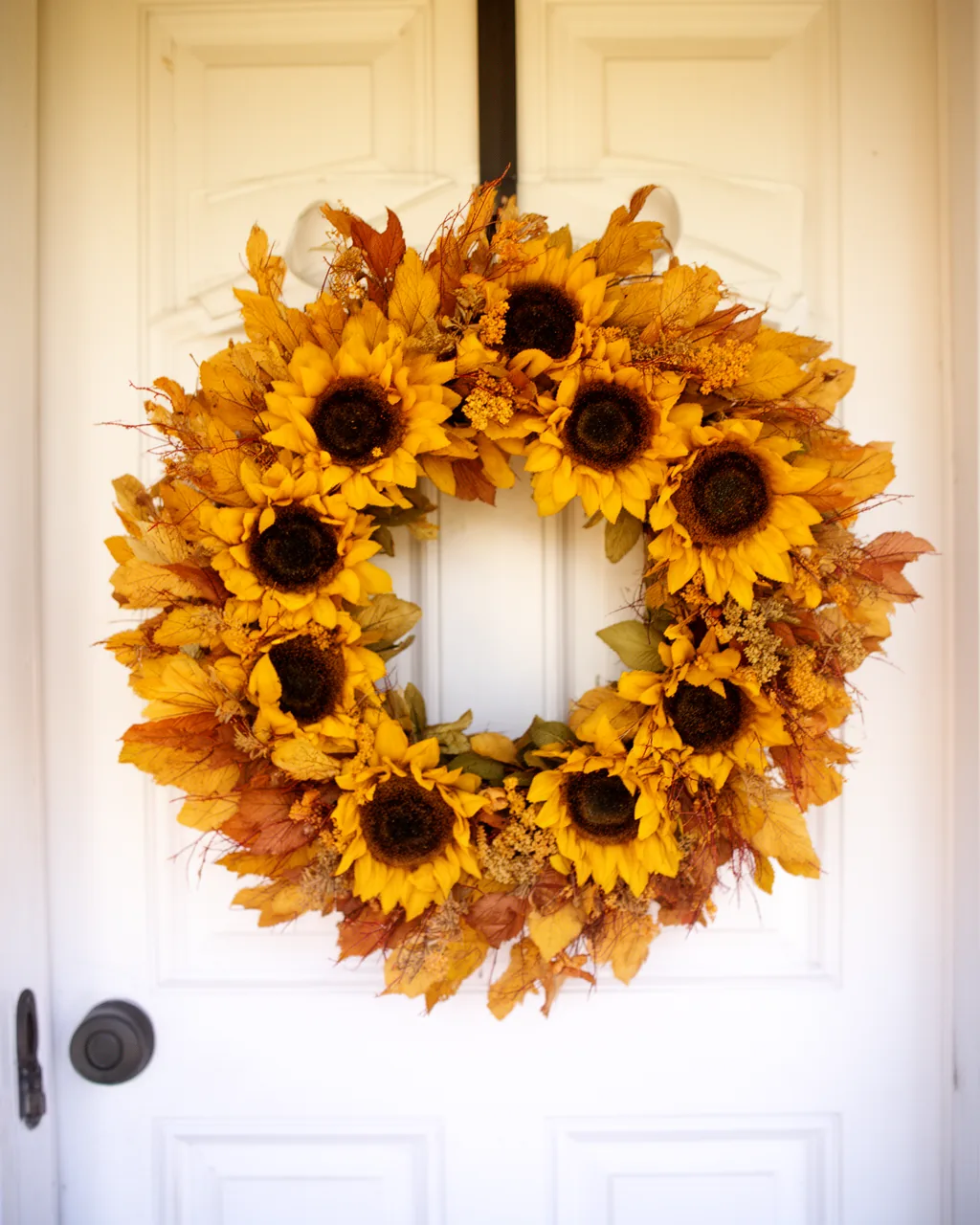 Sunflower and mustard yellow wreath on a white door