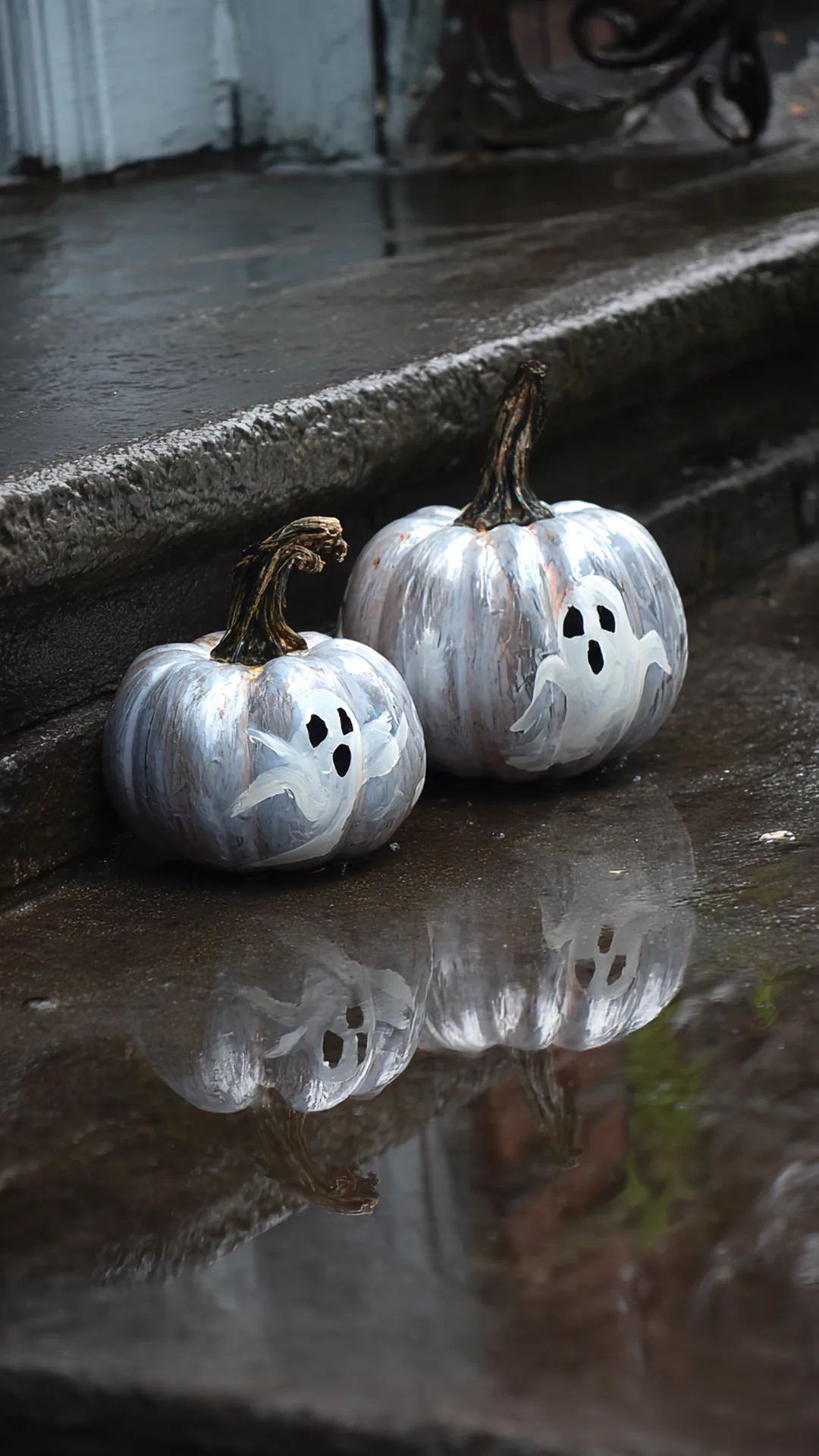 painted ghost faces on real pumpkins on wet porch steps — photo 1 of 5