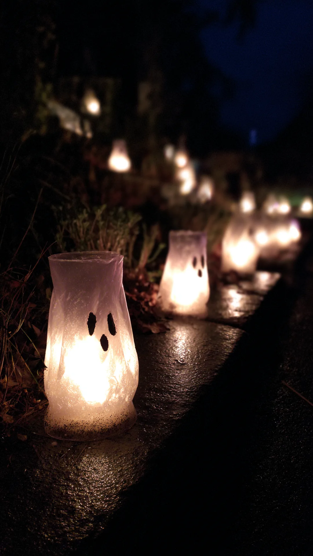 milk jug ghost luminaries glowing along a garden edge — photo 2 of 2