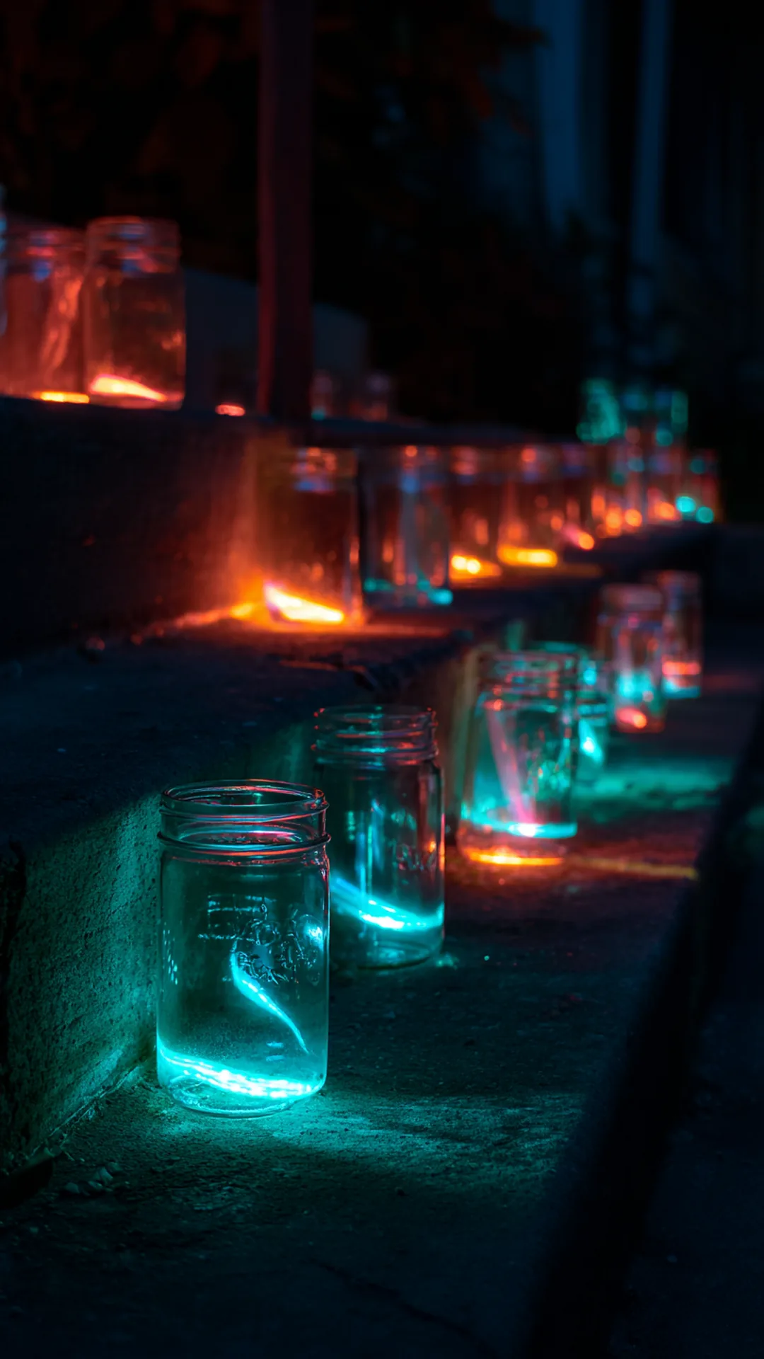glass jars filled with glowing sticks lining porch steps — photo 1 of 2