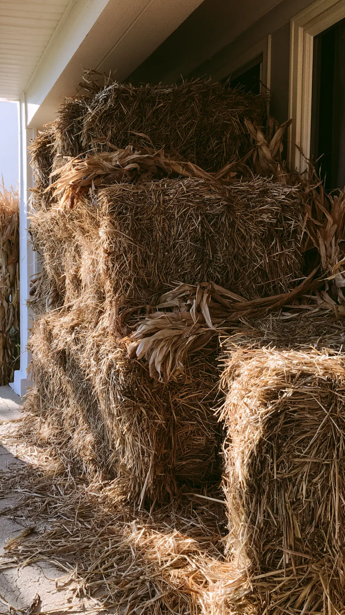 A stacked hay bale display anchored with rebar stakes on a porch, photo 1 of 3