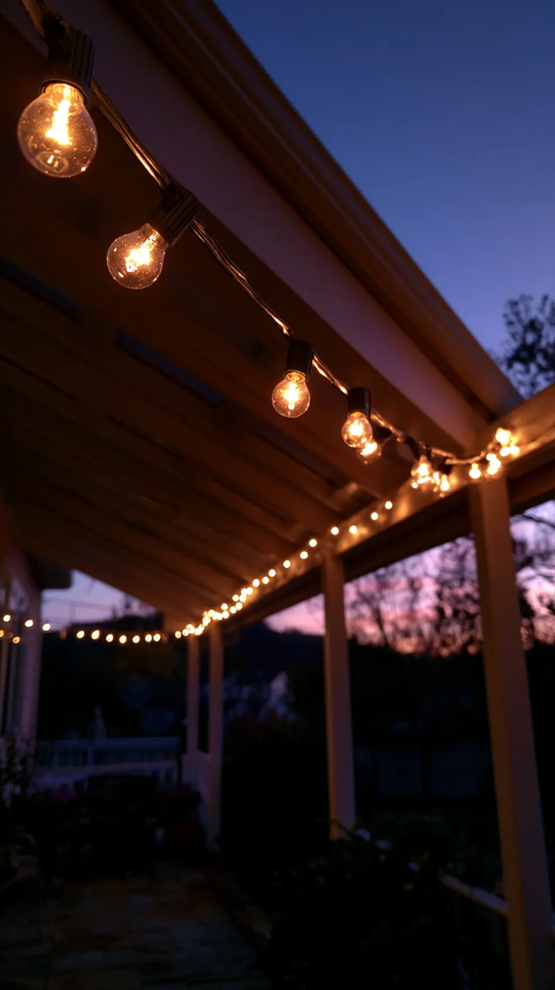 Warm white string lights hung along galvanized wire across a porch, photo 2 of 4