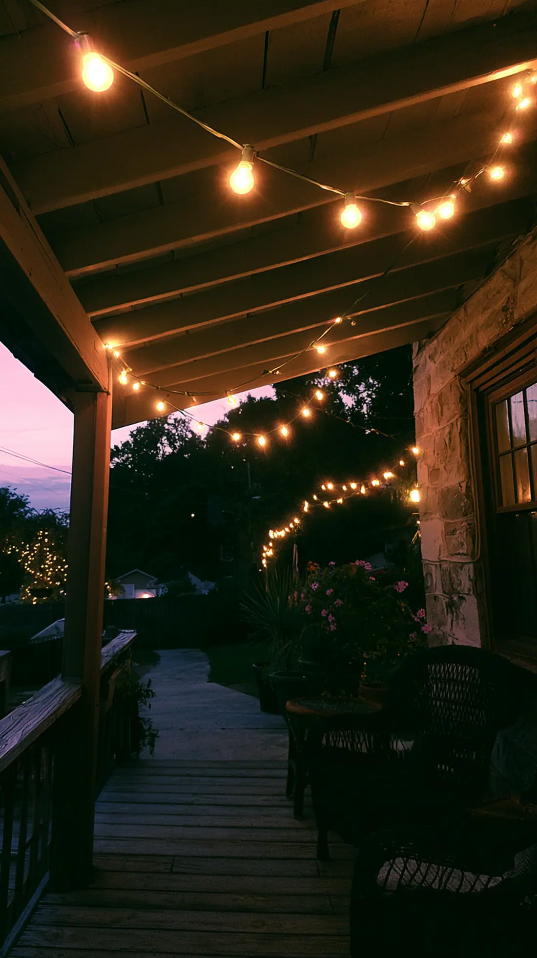 Warm white string lights hung along galvanized wire across a porch, photo 3 of 4