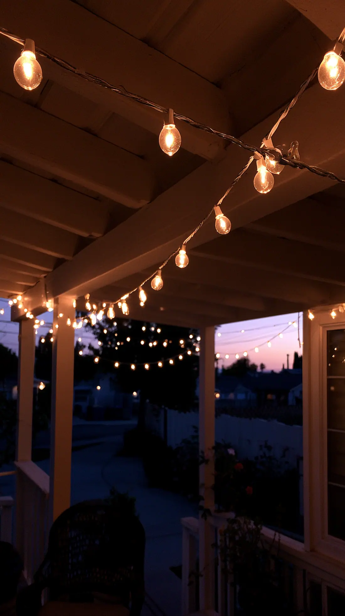 Warm white string lights hung along galvanized wire across a porch, photo 4 of 4