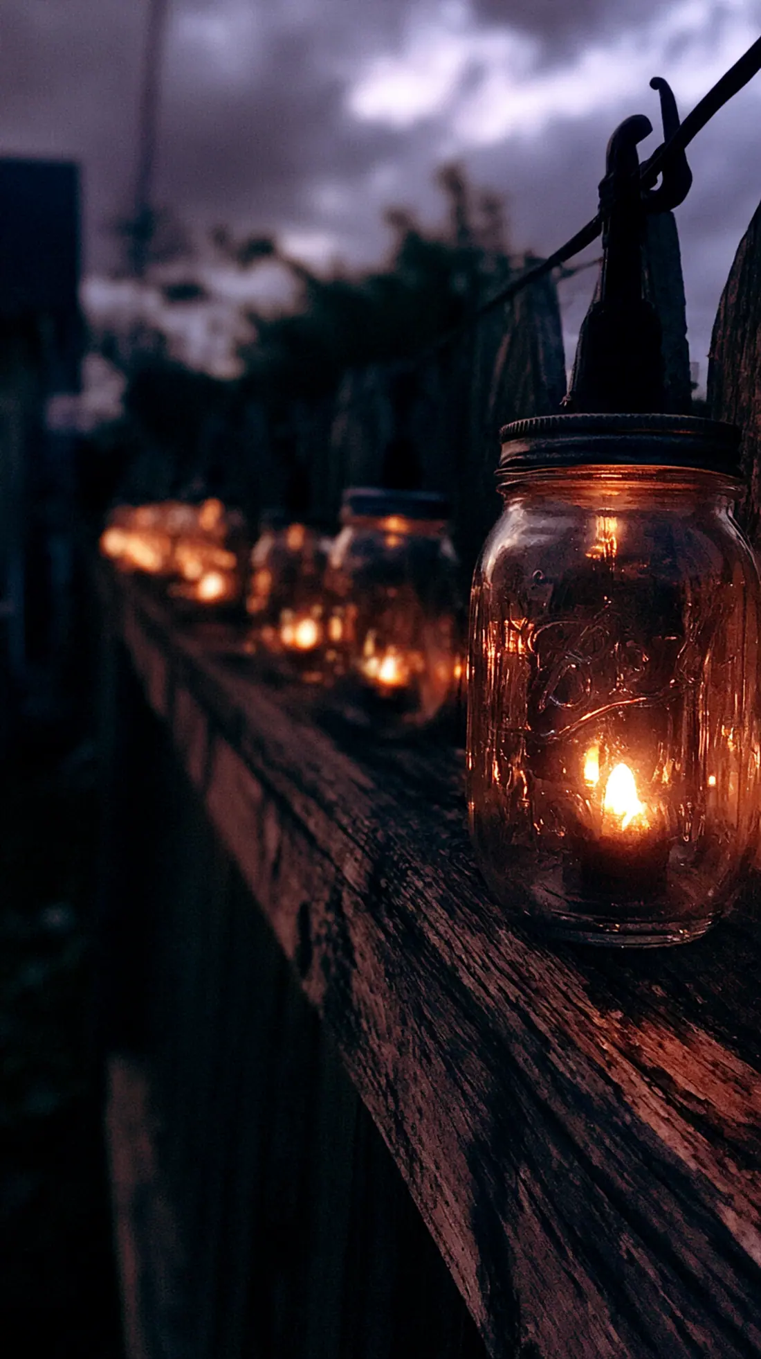 Battery-powered lanterns inside glass jars lining a backyard fence, photo 3 of 4
