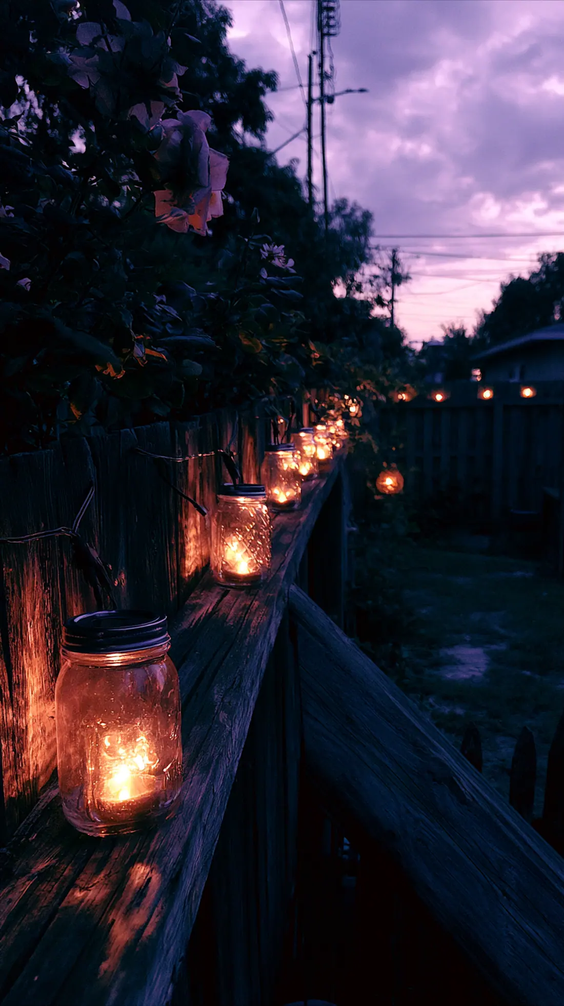 Battery-powered lanterns inside glass jars lining a backyard fence, photo 4 of 4