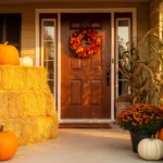 Cozy fall front porch with golden hay bales pumpkins and mums